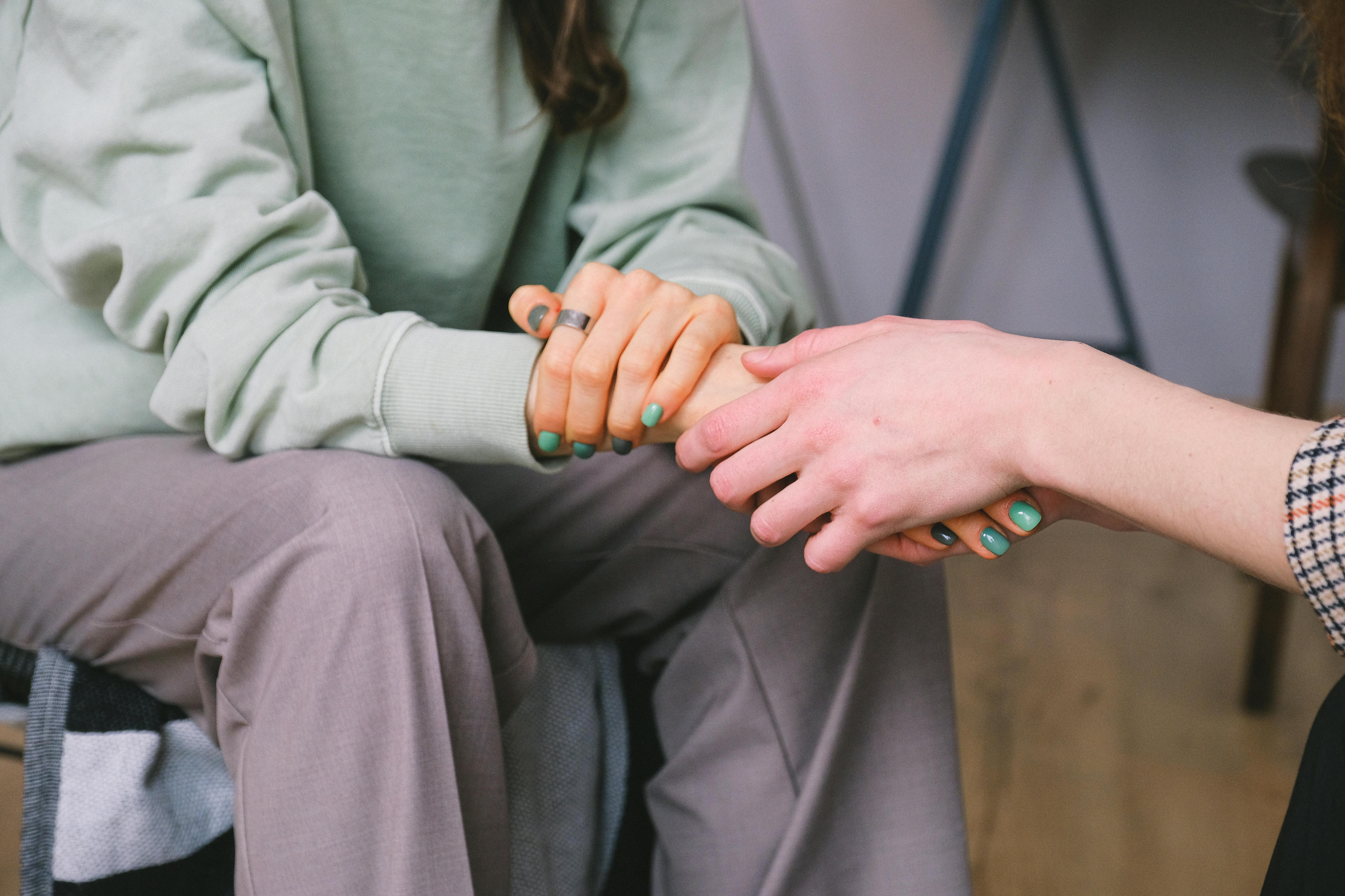 Two people holding hands, offering comfort and support.