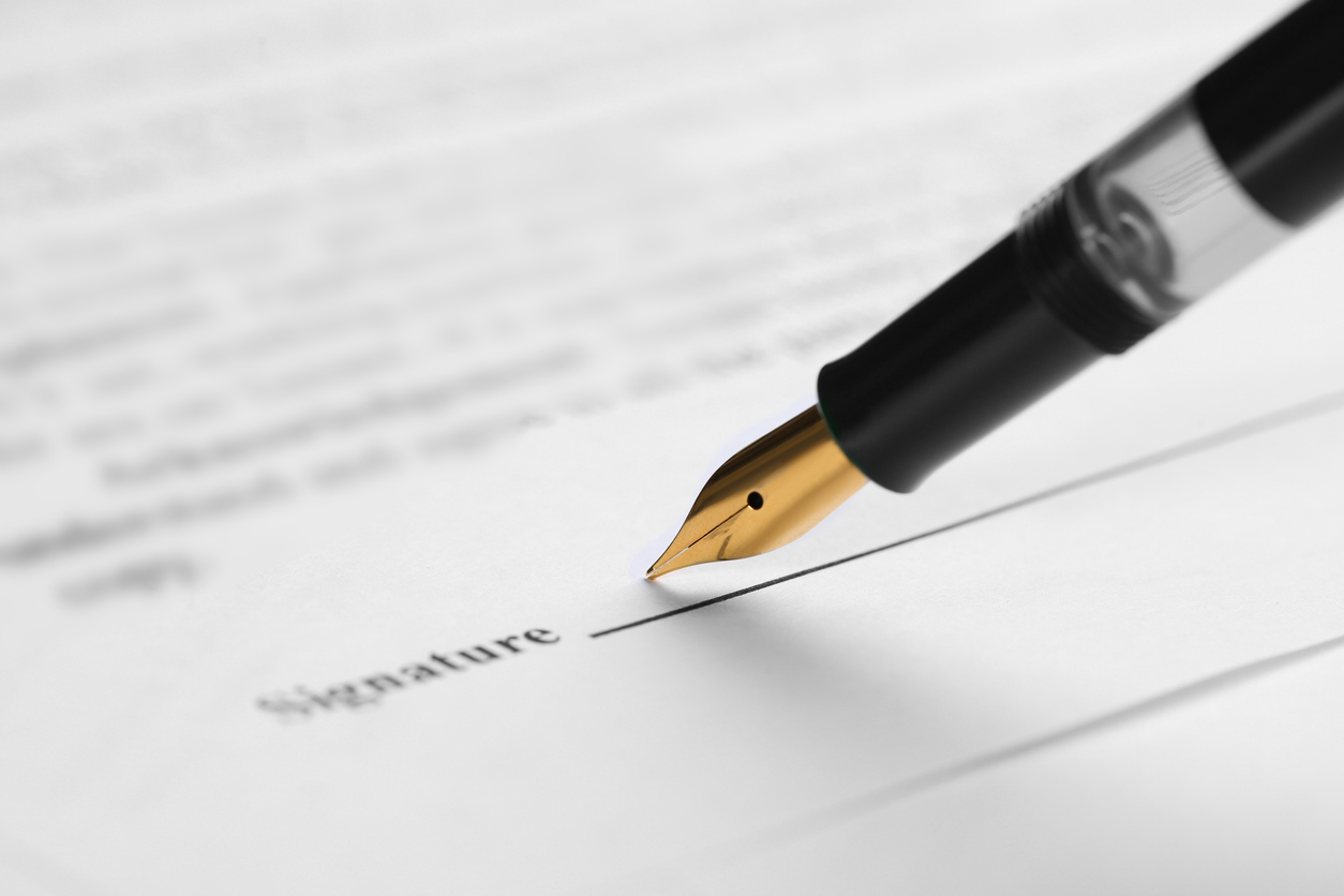 a pen hovering over paper that says "signature"