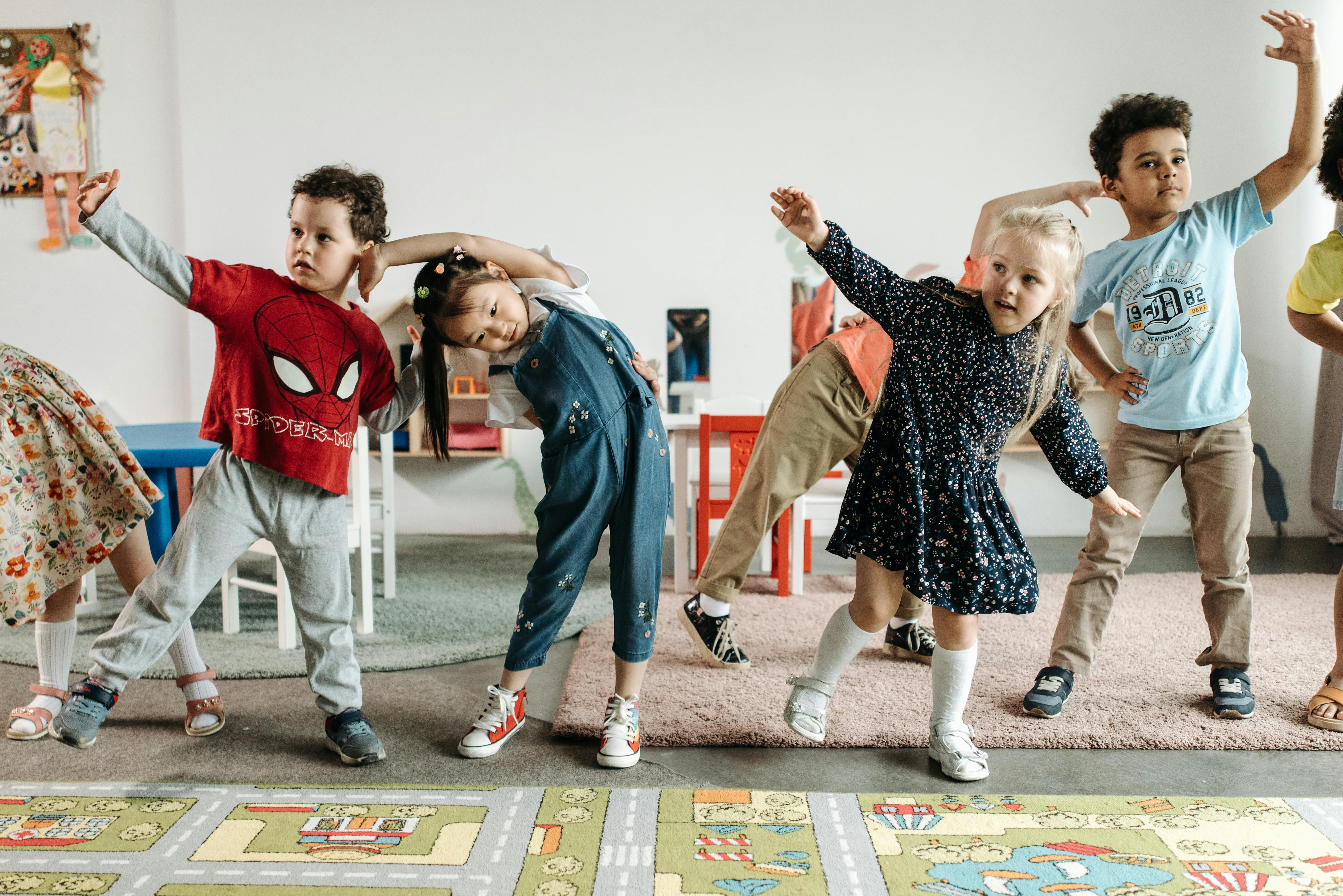 Young children stretching together in a classroom, smiling and having fun.