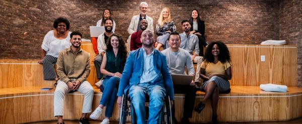 Diverse group of people smiling and posing in a modern, wood-paneled meeting space.