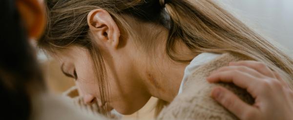 Person comforting a woman who appears sad with a hand on her shoulder.