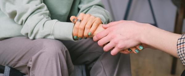 Two people holding hands, offering comfort and support.