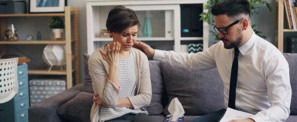 Man comforting a sad woman during a counseling session on a sofa.