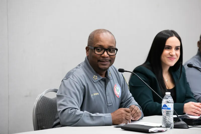Man and woman sitting at a table with microphones, smiling during a panel discussion.