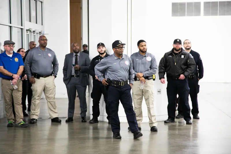 Group of security personnel standing indoors in a spacious, well-lit area.