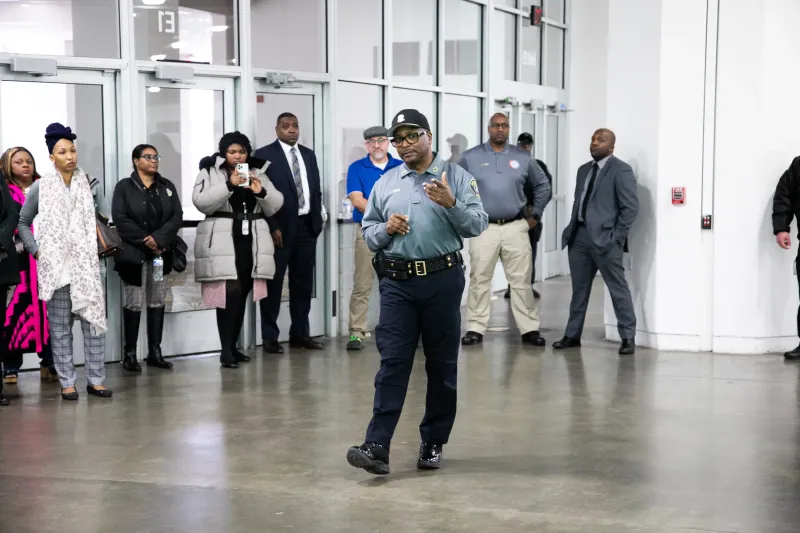 Police officer speaking to a group of people in a modern indoor setting.