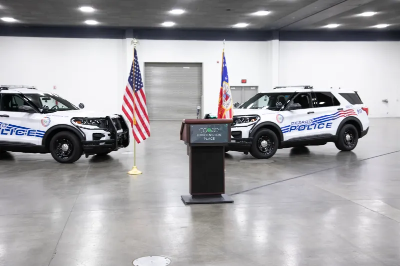 Police cars, podium, and American flags inside a convention hall.