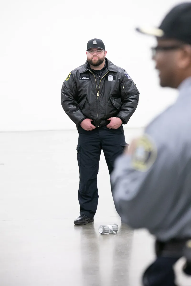 Two security guards in uniform stand in a bright, empty room.