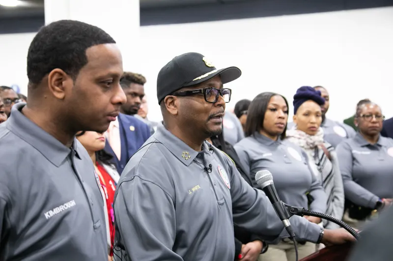 Group of uniformed people at a podium, listening attentively indoors.
