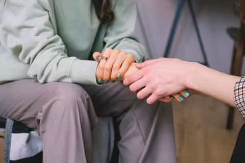 Two people holding hands, offering comfort and support.